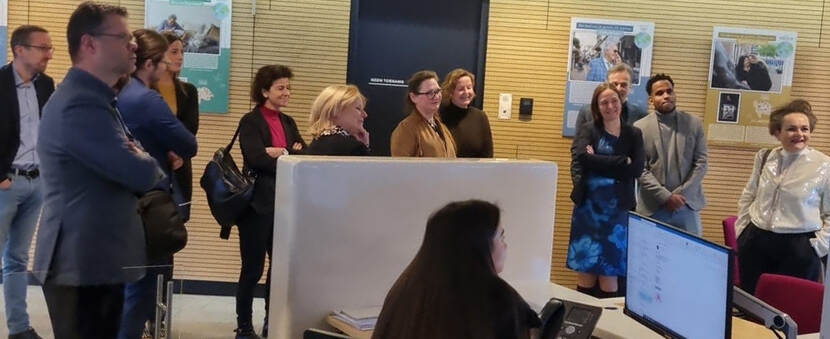 Meerdere mensen in een kantoorruimte die naar iemand luisteren