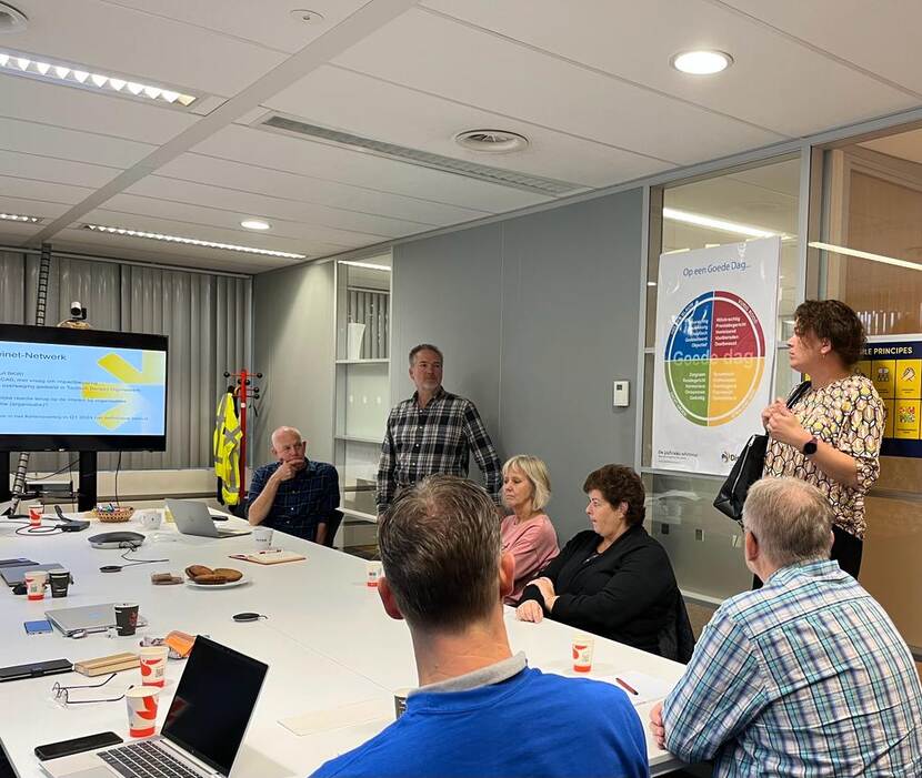 Groep mensen in een vergaderzaal tijdens een presentatie